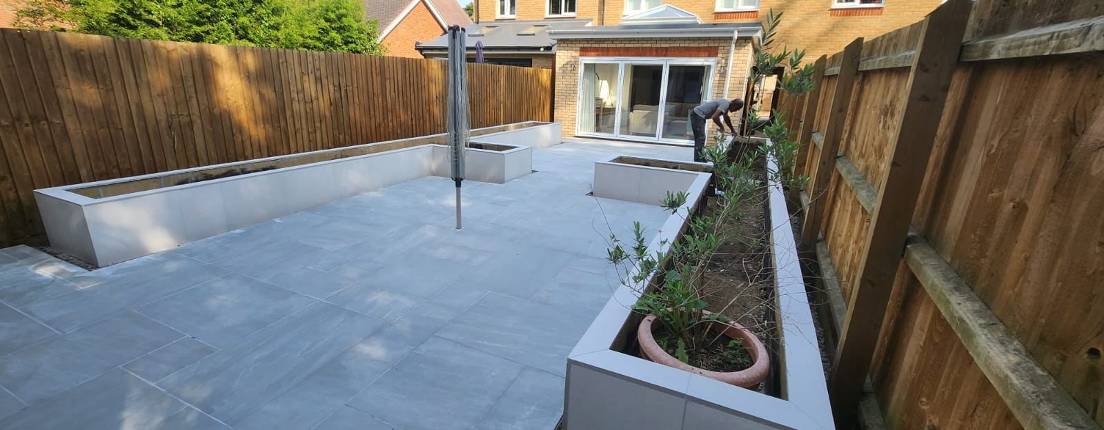 Grey porcelain patio with rendered raised planters being planted up in a new Essex garden