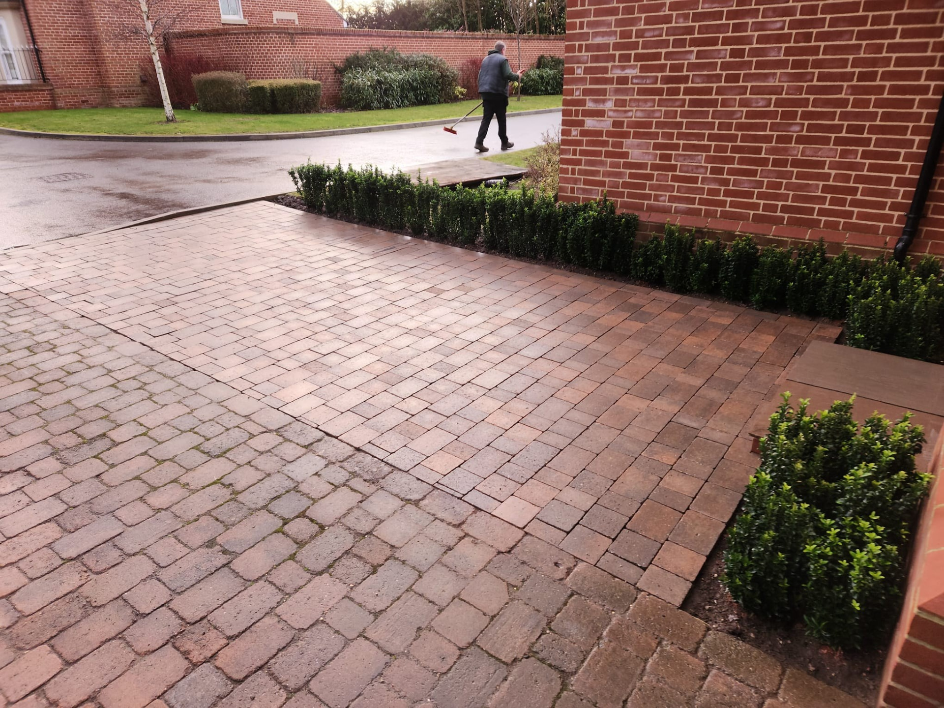 Finished red block paved driveway with clean edge course and low hedge border